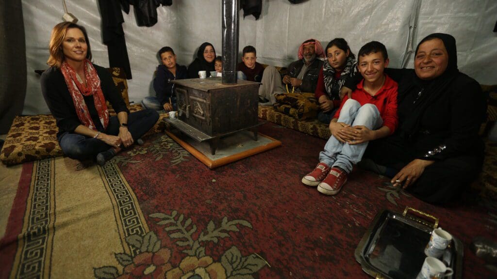 A group of people sitting around in front of a fire place.