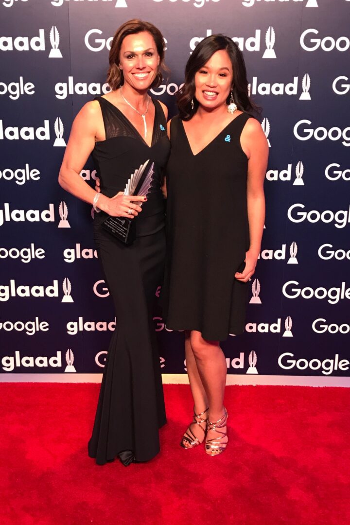 Two women in black dresses standing on a red carpet.