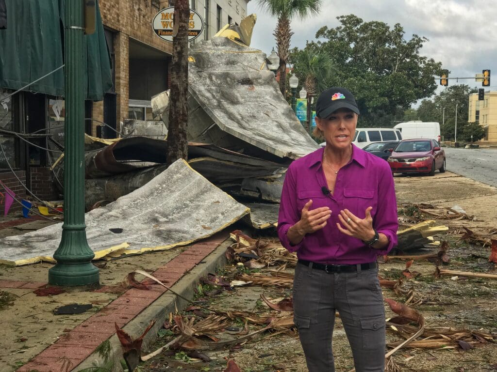 A woman standing in front of debris and trees.