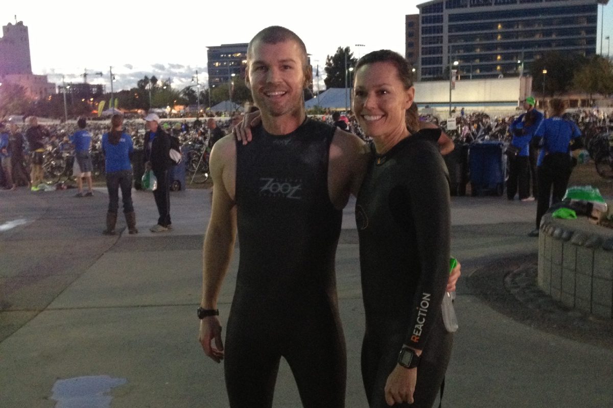 A man and woman in wetsuits posing for the camera.