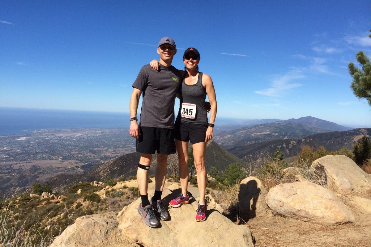 A man and woman standing on top of a mountain.