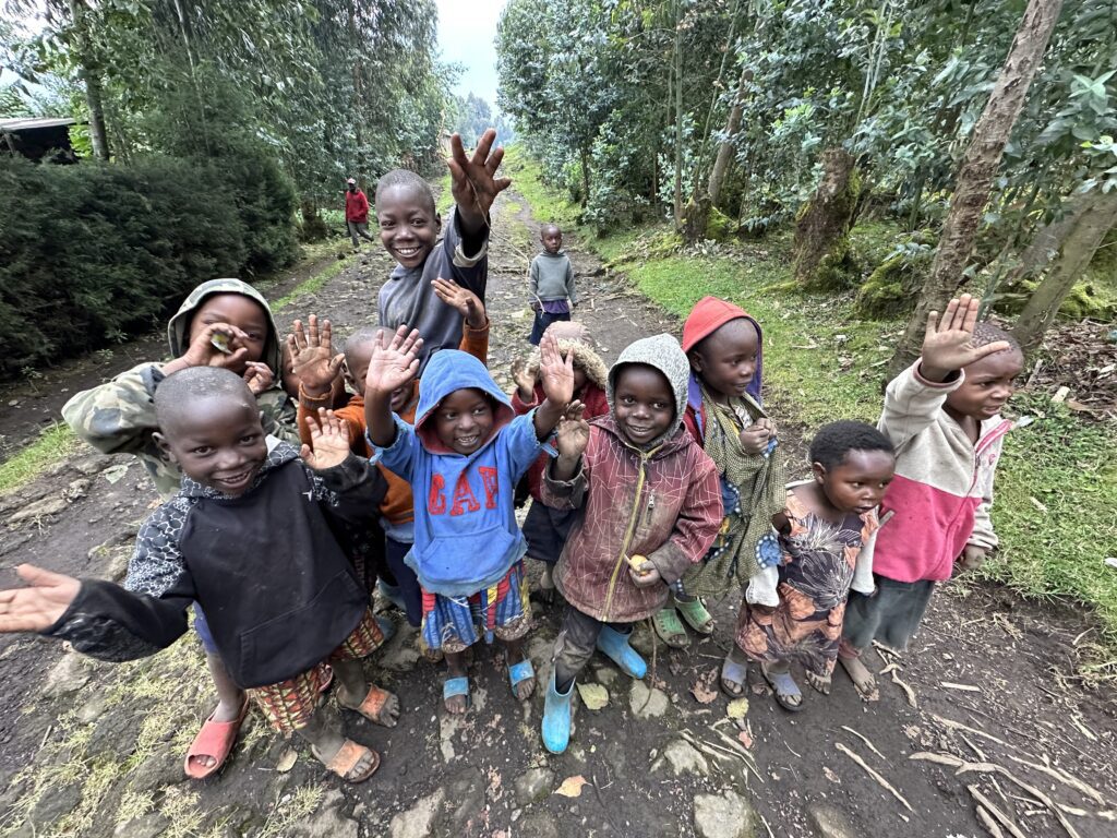 A group of children standing on top of a dirt road.