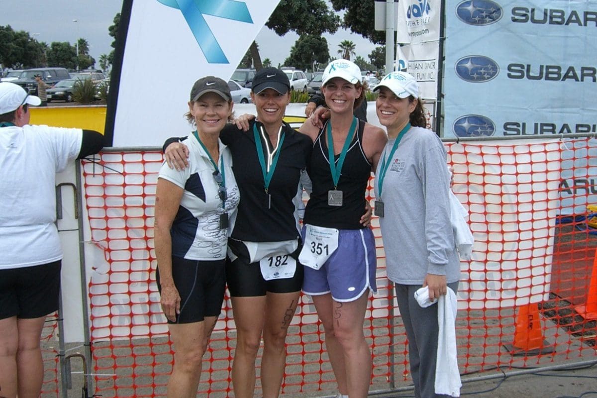 Four women standing next to each other in front of a wall.