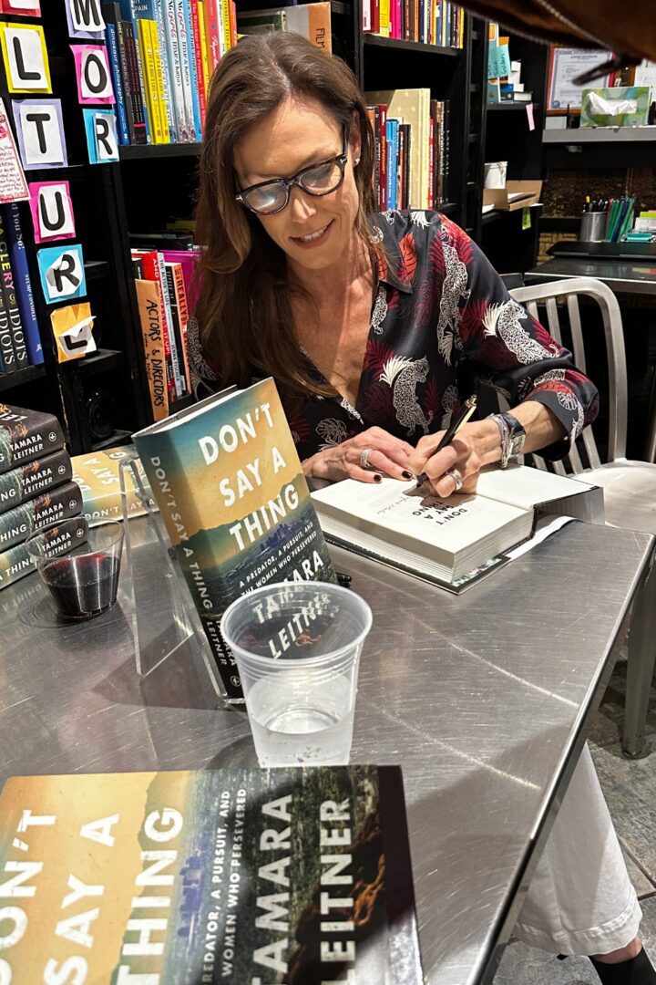 A woman writing on a book at a table.